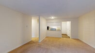 Located at 9855 SW Hall Blvd in Portland, Oregon, this single-floor unit offers a practical and comfortable layout designed for everyday living. The open living area is generously proportioned, finished with neutral-toned carpet and bright white walls that create a clean, airy atmosphere. A textured ceiling and baseboard heating are consistent throughout the space. A pass-through window connects the living area to the kitchen, enhancing the sense of openness between the two spaces.

The kitchen features wood-look vinyl flooring, white cabinetry, speckled countertops, a stainless steel sink, a black dishwasher, and a black range, with a hallway leading to additional rooms and storage beyond.

The living room includes a full wall of sliding glass doors dressed with vertical blinds, allowing abundant natural light and providing access to an outdoor area with greenery views. One accent wall features a tiled panel detail, adding subtle architectural character.

The bedrooms are carpeted and well-sized, each offering closet space and windows with vertical blinds that bring in natural light. Baseboard heaters are present in each room.

The bathroom is finished with wood-look flooring, a tub-shower combination with brushed nickel fixtures, a speckled countertop vanity, and clean white fixtures throughout, presenting a tidy and functional space.