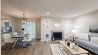 Located at 5072 Medlock Bridge Rd in Peachtree Corners, GA, this single-story 2-bedroom, 2-bathroom home offers a thoughtfully designed layout with modern finishes throughout. The entry hallway, finished with wood-look flooring, flows naturally toward the kitchen and dining areas. The kitchen is equipped with stainless steel appliances, including a range, over-the-range microwave, and refrigerator, complemented by granite-look countertops, white cabinetry, and a classic subway tile backsplash. A window brings in natural light and views of surrounding greenery. The dining room features wood-look flooring, a stylish geometric chandelier, and a large sliding door that fills the space with natural light. Both bedrooms are carpeted and include ceiling fans and windows with outdoor views. The spacious primary bedroom offers a generous closet with sliding doors and direct access to its own bathroom. The second bedroom also enjoys ample natural light and easy access to the second bathroom. Both bathrooms are finished with large-format gray tile in the shower and tub surrounds, lending a clean, contemporary feel. Textured ceilings and neutral warm-toned walls carry throughout, creating a cohesive and inviting atmosphere across the entire home.