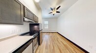 This compact one-bedroom, one-bathroom apartment at the Northern Hotel Apartments on N College Ave in Fort Collins, Colorado, offers an efficient and thoughtfully designed layout. Light hardwood flooring runs throughout, complemented by crisp white walls and bold dark-trimmed doorways that add a modern contrast.

The kitchen is equipped with stainless steel appliances, including a refrigerator, range, and dishwasher, alongside dark espresso cabinetry that provides ample storage. A wall-mounted mini-split unit ensures climate control year-round. The living and kitchen areas share an open feel, with a ceiling fan overhead and a window allowing natural light to fill the space.

The bedroom offers a quiet retreat with its own window fitted with blinds, a baseboard heating unit, and a built-in closet with hanging rod. The adjoining bathroom features a clean, minimalist design with a pedestal-style sink, a large mirror, a medicine cabinet, and a walk-in shower stall. Brushed nickel fixtures and grab bars add both style and functionality throughout the bathroom.

Located in the heart of Fort Collins, this apartment provides convenient access to local dining, shopping, and entertainment along the N College Ave corridor.