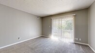 Located at 1121 S Paige St in Wichita, Kansas, this efficiently designed one-bedroom, one-bathroom unit offers a practical and comfortable single-floor layout. The living room serves as the heart of the space, featuring plush carpet flooring, neutral gray walls, a textured ceiling, and a large sliding glass door fitted with vertical blinds that fills the room with natural light and provides views of outdoor greenery. The entryway transitions from wood-look vinyl plank flooring into the carpeted living area, creating a clear and functional delineation of zones. The kitchen is a galley-style space equipped with white cabinetry, light-toned countertops with tile backsplash, and a built-in dishwasher, offering efficient use of the available space. The bedroom is a comfortably sized retreat with soft carpet, neutral walls, a ceiling fan with light fixture, and a window that allows natural light to brighten the room. A dedicated closet provides convenient storage. The bathroom features a full tub and shower combo with clean white tile surround and chrome fixtures. Throughout the unit, consistent neutral tones and clean finishes create a cohesive, understated aesthetic suited for comfortable everyday living.