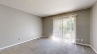Located at 1121 S Paige St in Wichita, Kansas, this efficiently designed one-bedroom, one-bathroom unit offers a practical and comfortable single-floor layout. The living room serves as the heart of the space, featuring plush carpet flooring, neutral gray walls, a textured ceiling, and a large sliding glass door fitted with vertical blinds that fills the room with natural light and provides views of outdoor greenery. The entryway transitions from wood-look vinyl plank flooring into the carpeted living area, creating a clear and functional delineation of zones. The kitchen is a galley-style space equipped with white cabinetry, light-toned countertops with tile backsplash, and a built-in dishwasher, offering efficient use of the available space. The bedroom is a comfortably sized retreat with soft carpet, neutral walls, a ceiling fan with light fixture, and a window that allows natural light to brighten the room. A dedicated closet provides convenient storage. The bathroom features a full tub and shower combo with clean white tile surround and chrome fixtures. Throughout the unit, consistent neutral tones and clean finishes create a cohesive, understated aesthetic suited for comfortable everyday living.