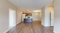 This single-story residence in Montgomery, Illinois offers a well-designed open-concept layout that seamlessly connects the kitchen, dining, and living areas. The kitchen serves as the focal point of the main living space, featuring a large central island with a built-in sink and white countertops, dark espresso cabinetry, stainless steel appliances including a range, microwave, and refrigerator, and pendant lighting overhead. A chandelier illuminates the adjacent dining area, while recessed lighting throughout enhances the bright, airy atmosphere. Wood-look luxury vinyl plank flooring extends across the main living areas, adding warmth and visual continuity.

A dedicated living area offers direct outdoor access through a glass-paneled door, with a ceiling fan and natural light from multiple windows. The bedroom is carpeted and generously sized, featuring dual windows, a ceiling fan, and a walk-in closet with built-in shelving. The primary bathroom includes a dark-cabinetry vanity with a white countertop and a full tub-shower combination. A second bathroom similarly features a tub-shower unit with a tall storage cabinet. A separate laundry area accommodates a full-sized washer, conveniently accessible from the kitchen.