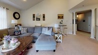 Located at 1395 Stone Creek Lane in Charlottesville, Virginia, this two-story home offers a thoughtfully designed layout with a warm, neutral aesthetic carried consistently across all levels. The main living area features a vaulted ceiling that adds a sense of openness and volume, with soft carpet underfoot and walls in a light, creamy tone. A cozy fireplace with tile surround anchors the room, complemented by a wall-mounted television and windows with sheer curtains that allow natural light to filter in comfortably.

The kitchen is equipped with light maple cabinetry, dark countertops, tile flooring, and a full suite of white appliances. A breakfast bar connects the kitchen to an adjacent dining or flex space. Bathrooms throughout the home feature light maple vanities, tile flooring, and clean, functional layouts.

The primary bedroom is generously proportioned, with plush carpet, multiple closets, and direct access to a private bathroom complete with a shower-tub combination. Additional bedrooms offer ample closet storage and carpeted floors. The overall ambiance of the home is understated and move-in ready, with a cohesive design that balances practicality with comfort throughout both floors.