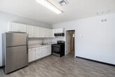 Located at 2580 Wild Pines Ct in Naples, FL, this one-bedroom, one-bathroom unit offers an efficiently designed single-floor layout ideal for comfortable living. The open-concept great room seamlessly combines the living, dining, and kitchen areas into one cohesive space, maximizing functionality. The kitchen is outfitted with crisp white shaker-style cabinetry, a classic white subway tile backsplash, light-toned countertops, and stainless steel appliances including a refrigerator, range, and over-the-range microwave. Light-toned luxury vinyl plank flooring runs throughout the main living areas, adding warmth and easy maintenance. The bedroom offers a well-proportioned retreat with soft gray walls, the same durable vinyl plank flooring, and a sliding glass closet door. The bathroom features a white vanity with a single sink, a medicine cabinet mirror, and a tiled walk-in shower. A utility room provides added convenience for storage or laundry needs. The unit also includes a private patio, offering an outdoor space to enjoy the Florida sunshine. Neutral gray walls and consistent flooring throughout lend the space a clean, modern aesthetic.