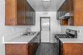 Located at 11050 Cynthia Cir in Garden Grove, CA, this single-floor, 2-bedroom, 2-bathroom home offers a practical and well-organized layout. The open living room features light wood-style vinyl flooring, a ceiling fan, a wall-mounted AC unit, and multiple windows fitted with blinds that allow natural light to fill the space, creating a bright and airy atmosphere.

The galley-style kitchen is efficiently designed with rich dark wood cabinetry lining both walls, white countertops, a stainless steel gas range, an under-cabinet range hood, and a double sink. A stacked washer and dryer unit is conveniently integrated at the end of the kitchen, providing in-unit laundry.

Both bedrooms feature soft carpeting and neutral white walls. The primary bedroom offers a generous footprint, while the secondary bedroom includes a large sliding double-door closet and a window overlooking outdoor greenery. Both rooms provide a clean, versatile canvas for furnishing.

The two bathrooms are finished with dark wood vanities topped with granite-style counters and dark vinyl plank flooring. One bathroom includes a shower-tub combination, while the other is more compact in layout. A hallway and dedicated closet space round out the home's interior, contributing to overall storage and functionality throughout.