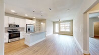 This single-story, 2-bedroom, 3-bathroom home offers a thoughtfully designed open-concept layout with modern finishes throughout. Light wood-tone flooring flows seamlessly across all rooms, creating a cohesive and airy feel.

The kitchen and living area form the heart of the home. The kitchen is equipped with white shaker cabinetry, a subway tile backsplash, stainless steel appliances including a refrigerator with ice maker, a gas range, and a microwave. A central island with a granite countertop and undermount sink serves as both a prep space and casual gathering spot, illuminated by stylish globe pendant lights. Built-in open shelving adds functional character. The adjacent living room features a ceiling fan and large windows with access to an exterior door, filling the space with natural light.

Both bedrooms feature ceiling fans, large windows with outdoor views, and walk-in closets outfitted with wire shelving systems. The primary bedroom offers a generously sized walk-in closet and its own dedicated bathroom. The bathrooms are well-finished, with one featuring a soaking tub surrounded by elegant marble-style tile walls and granite vanity countertops.

A dedicated laundry room houses a full-size washer and dryer. Two hallways provide smooth circulation throughout the layout, completing this functional and stylish home.