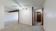 Located at 710 SW Fairlawn Rd in Topeka, Kansas, this single-floor home offers five bedrooms and one bathroom within a compact, efficiently organized layout. The living areas feature neutral-toned carpet throughout, textured ceilings, and dark wood-trimmed accents that lend a classic character to the interior. A ceiling fan with a light fixture provides both airflow and overhead lighting in the main living space, which connects to a hallway corridor lined with dark wood bi-fold closet doors. The spacious primary bedroom includes two closets side by side and a window that allows natural light to filter in. Additional bedrooms are carpeted and include individual closet access. A dedicated walk-in closet with built-in shelving and hanging rods offers generous storage capacity. The kitchen features dark wood cabinetry with ample upper and lower storage, white laminate countertops, a coil-top electric range with overhead ventilation, and wood-look flooring that adds warmth to the space. The bathroom is finished with wood-look flooring, a vanity with white cabinetry, and a towel bar. Two hallways connect the rooms, enhancing the flow throughout the home. Overall, the space presents a functional and straightforward layout suitable for multi-occupant living.