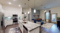 This single-story, 2-bedroom, 2-bathroom residence in Houston, TX offers a thoughtfully designed open-concept floor plan that maximizes functionality and flow. The kitchen serves as a central focal point, featuring white shaker-style cabinetry extending to the ceiling, granite countertops, a subway tile backsplash, and a full suite of stainless steel appliances. A large granite-topped island with an undermount sink provides seating for multiple guests and connects seamlessly to the living area. Pendant lighting above the island and recessed ceiling lights enhance the bright, airy atmosphere, while wood-style flooring runs throughout the main living areas.

The living room features a ceiling fan, neutral and slate-blue accent walls, and a glass door that invites natural light and outdoor access. Both bedrooms are carpeted and well-sized, each with large windows, ceiling fans, and ample natural light. The primary bedroom connects to an en-suite bathroom equipped with a walk-in glass shower, granite vanity, and wood-style flooring. The second bathroom mirrors the same refined aesthetic, offering a full tub-shower combination with tile surround and a granite vanity. Together, these spaces create a cohesive, modern living environment.