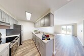 Located at 7524 35th Ave SW in Seattle's West Seattle neighborhood, this one-bedroom, one-bathroom unit offers a well-designed, efficiently laid out single-floor living space. A welcoming hallway with wood-look flooring leads into the heart of the home.

The galley-style kitchen is a standout feature, showcasing gray shaker cabinetry, light granite-style countertops, stainless steel appliances including a refrigerator and range, a skylight overhead, and a peninsula that opens directly to the living area. The open-concept living room benefits from vaulted ceilings, a ceiling fan, abundant natural light, and sliding glass door access to an outdoor space, creating an airy and expansive feel.

The bedroom is carpeted and generously sized, featuring a closet with bifold doors, a window with outdoor views of surrounding greenery, and easy access to the adjacent bathroom. The full bathroom is finished with gray vanity cabinetry, granite-style countertops, wood-look flooring, and a tub/shower combination with chrome fixtures.

Wood-look flooring flows throughout the main living areas, tying the space together with a clean, modern aesthetic. Recessed lighting and ample natural light complete the bright, contemporary character of this Seattle home.
