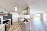Located at 7524 35th Ave SW in Seattle's West Seattle neighborhood, this one-bedroom, one-bathroom unit offers a well-designed, efficiently laid out single-floor living space. A welcoming hallway with wood-look flooring leads into the heart of the home.

The galley-style kitchen is a standout feature, showcasing gray shaker cabinetry, light granite-style countertops, stainless steel appliances including a refrigerator and range, a skylight overhead, and a peninsula that opens directly to the living area. The open-concept living room benefits from vaulted ceilings, a ceiling fan, abundant natural light, and sliding glass door access to an outdoor space, creating an airy and expansive feel.

The bedroom is carpeted and generously sized, featuring a closet with bifold doors, a window with outdoor views of surrounding greenery, and easy access to the adjacent bathroom. The full bathroom is finished with gray vanity cabinetry, granite-style countertops, wood-look flooring, and a tub/shower combination with chrome fixtures.

Wood-look flooring flows throughout the main living areas, tying the space together with a clean, modern aesthetic. Recessed lighting and ample natural light complete the bright, contemporary character of this Seattle home.