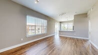 This single-story residence in Farmers Branch, Texas offers a thoughtfully designed layout across a comfortable footprint, accommodating two bedrooms and two full bathrooms. The open-concept living room and kitchen area serve as the heart of the home, featuring warm wood-style luxury vinyl plank flooring, neutral taupe walls, and generous natural light streaming through large windows with views of the surrounding area. The kitchen is equipped with dark espresso cabinetry extending to the ceiling for ample storage, stainless steel appliances including a side-by-side refrigerator with ice and water dispenser, a range, and microwave. A peninsula with a white countertop and pendant lighting connects the kitchen to the living area, enhancing the open feel.

Both bedrooms are finished with plush carpet and feature windows that invite natural light. The spacious primary bedroom connects to a bathroom with a dark-cabinet vanity, white countertops, and wood-style flooring. The secondary bathroom includes a tub-shower combination with white subway tile surround. Two closets provide organized storage with wire shelving systems. A dedicated laundry area accommodates a full-size washer and dryer with overhead shelving, completing this well-equipped residence.