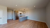 This single-floor space showcases a contemporary design with a cohesive neutral palette and light hardwood flooring that runs throughout the unit. The open-concept kitchen and living area serves as the heart of the space, anchored by a large central island with a built-in sink and a sleek, wood-toned finish. The kitchen is outfitted with white upper cabinetry, warm wood lower cabinets, a white subway tile backsplash, and a full suite of stainless steel appliances, including a refrigerator, gas range, and microwave. A modern industrial-style pendant light fixture hangs above the island, complementing the recessed lighting overhead. The expansive open living area flows seamlessly from the kitchen, offering generous space bathed in ambient light.

The bedrooms feature large windows that allow abundant natural light and offer outdoor views, with rich hardwood flooring adding warmth. One bedroom provides direct access to a private balcony. The bathrooms are finished in a clean, modern style—one includes a glass-enclosed walk-in shower with white subway tile, while the second features a full tub-shower combination with matching tile surround. Black hardware accents appear consistently throughout, tying the design together with a polished, modern touch.