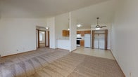 This single-floor unit offers a practical and well-organized layout designed to maximize functionality. The open-concept living and dining area is finished with neutral carpet and flows directly into the kitchen, creating a connected, airy feel. Vaulted ceilings in the main living space add a sense of height and openness, complemented by ceiling fans with pendant lighting overhead.

The kitchen features warm-toned oak cabinetry, light countertops, and tile flooring. It is equipped with a full suite of appliances, including a white refrigerator, electric range, and black dishwasher. A peninsula separates the kitchen from the living area, offering additional prep and serving space.

Adjacent to the kitchen, a dedicated laundry area houses a side-by-side washer and dryer, conveniently located behind double doors. The full bathroom includes a soaking tub with shower, an oak vanity with sink, and tile flooring throughout.

The bedrooms are carpeted and include generous closet space. One room features a wide sliding-door closet, while another benefits from a large walk-in closet with full-length hanging rods. The living room opens to an outdoor deck through a sliding glass door, bringing in natural light and outdoor views.