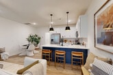 This two-story home in Charlotte, NC offers 3 bedrooms and 4 bathrooms thoughtfully distributed across two floors. The main level centers around an open-concept kitchen and living area finished with light hardwood-style flooring. The kitchen is a standout, featuring crisp white shaker cabinetry, a bold navy blue island with a quartz countertop, stainless steel appliances, a tile backsplash, and dual matte black pendant lights. A pantry and convenient half bath round out the first floor, which also includes an attached garage. The living room receives natural light through large windows dressed with linen curtains, creating a bright and welcoming atmosphere. Upstairs, the primary bedroom offers a comfortable retreat with a ceiling fan and dedicated closet. Two additional bedrooms share well-appointed bathrooms, each featuring white vanities with quartz countertops and hardwood-style flooring. A dedicated laundry room and multiple closets add to the home's functional layout. With five closets, three hallways, and two staircases, the floor plan is designed to maximize both storage and flow, making this Charlotte home a well-organized and stylish living space.