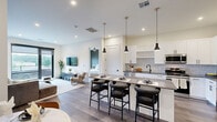 Located at 1000 Vermella Way in New Brunswick, NJ, this thoughtfully designed 2-bedroom, 2-bathroom residence offers a seamless blend of modern aesthetics and functional living. The open-concept kitchen, dining, and living area serves as the heart of the home, featuring wide-plank hardwood-style flooring in a herringbone pattern, recessed lighting, and floor-to-ceiling sliding glass doors that lead to a private balcony with open outdoor views. The kitchen is appointed with white shaker cabinetry, dark hardware, quartz countertops, a mosaic tile backsplash, and a full suite of stainless steel appliances, including a gas range. A center island with pendant lighting provides additional seating and workspace. The primary bedroom is generously proportioned, featuring a sliding glass door to the balcony, a ceiling fan, and a spacious walk-in closet with custom built-in shelving and drawers. The second bedroom is accented by a bold feature wall with decorative wallpaper and its own dedicated closet. Both bathrooms are finished with large-format tile surrounds and matte black fixtures. The residence includes two well-sized closets throughout, ensuring ample storage across the entire home.
