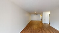 This 680 square foot apartment offers a well-designed living space with one bedroom and one bathroom. The unit features warm wood flooring throughout, creating a cohesive and inviting atmosphere. The living room is spacious and bright, with a large window allowing natural light to flood the area. A modern ceiling fan provides both illumination and air circulation.

The kitchen is equipped with wooden cabinets, a stainless steel refrigerator, and a sink with ample counter space. Adjacent to the kitchen is a convenient in-unit laundry area with a washer and dryer. The bathroom features a white tiled shower-tub combination with chrome fixtures.

The bedroom, measuring 150 square feet, includes a closet for storage. Ceiling fans in both the living room and bedroom offer comfort and energy efficiency. The apartment's layout maximizes the use of space, making it feel larger than its actual square footage. With its practical amenities and thoughtful design, this apartment provides a comfortable living environment in a compact footprint.