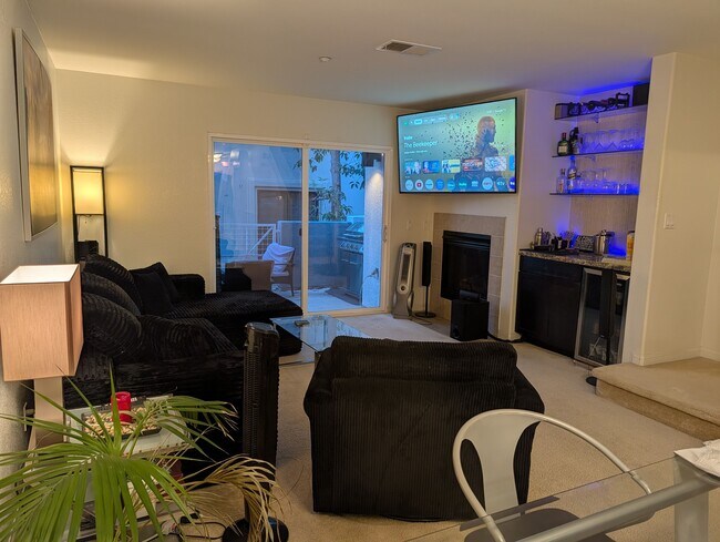 Sala de estar amueblada con TV, chimenea, bar, mininevera y centro de entretenimiento oculto. Balcón. - 3542 Shoreline Bluff Lane