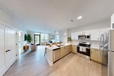 Located at 2111 Packard St in Ann Arbor, MI, this well-designed 2-bedroom, 2-bathroom residence offers a thoughtfully organized single-floor layout. The open-concept living area is the heart of the home, where the kitchen, dining, and living spaces flow seamlessly together under a bright, white ceiling. Large windows and a glass balcony door flood the space with natural light while framing views of the surrounding neighborhood.

The contemporary kitchen features a two-tone design with white upper cabinets and warm wood-toned lower cabinets, complemented by stainless steel appliances including a range, microwave, refrigerator, and dishwasher. A peninsula with a quartz countertop provides additional prep space and casual bar seating beneath pendant lighting. Light wood-style flooring extends throughout the main living areas, enhancing the airy, modern aesthetic.

The primary bedroom offers a calm, neutral retreat with plush carpeting and ample closet space. The bathrooms are cleanly appointed, with one featuring a glass-enclosed shower with contemporary tile work and matte black fixtures. Additional highlights include in-unit laundry, a utility room, and three closets for generous storage. The overall ambiance is bright, clean, and modern throughout.