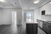 Located at 49 Walnut Street South in Hamilton, Ontario, this modern one-bedroom, one-bathroom unit offers a well-designed open-concept layout across a single floor. Light hardwood flooring flows throughout the space, complementing the clean, contemporary aesthetic found in every room.

The kitchen is a standout feature, equipped with stainless steel appliances including a refrigerator, electric range, and built-in microwave. A central island with a white quartz countertop provides additional prep space and casual seating. Two-tone cabinetry — white upper cabinets paired with warm wood-toned lower cabinets — adds visual depth, while a tile backsplash ties the design together. Floor-to-ceiling windows at the end of the open living area flood the space with natural light and offer expansive city views.

The bedroom is a quiet, comfortable retreat featuring a full-height built-in closet with wood-panel doors and matte black hardware, maintaining the unit's cohesive modern style. The bathroom continues this design language with a floating wood-toned vanity, white quartz countertop, undermount sink, and a framed mirror with overhead lighting. The result is a well-appointed, functional space with a clean and contemporary character throughout.