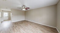Located at 160 Stateline Rd in Clarksville, Tennessee, this two-bedroom, two-bathroom two-story home offers a practical and comfortable layout spread across two floors. The main level houses the combined kitchen and living area, two bathrooms, and an entry. The living room features light luxury vinyl plank flooring, neutral beige walls, white trim, and a ceiling fan with integrated lighting, creating a bright and airy atmosphere. Natural light filters in through multiple windows fitted with blinds. The entry area includes a front door flanked by windows that bring in pleasant outdoor views. The kitchen is equipped with warm honey-toned wood cabinetry, light countertops, a double sink, and black appliances including a refrigerator, range, and dishwasher, complemented by matching LVP flooring. Both bathrooms feature wood-toned vanities and LVP flooring. The upper level is home to the two bedrooms, both finished with plush carpeting and neutral walls. The primary bedroom is a comfortable size and includes a ceiling fan, a window with natural light, and access to closet space. The second bedroom also offers a window and a double-door closet for ample storage. A staircase connects the two floors, adding to the home's efficient and functional design.