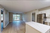 This 2-bedroom, 2-bathroom residence offers a thoughtfully designed single-floor layout that maximizes both comfort and functionality. Light hardwood flooring flows throughout the main living areas, lending a bright and cohesive aesthetic. The open-concept kitchen is a standout feature, equipped with white shaker cabinetry, a classic white subway tile backsplash, quartz countertops, a marble-look island, and a full suite of stainless steel appliances including a refrigerator, dishwasher, electric range, and built-in microwave. The kitchen transitions seamlessly into the living room, which benefits from large sliding glass doors that fill the space with natural light and offer views of surrounding greenery. The primary bedroom is a generously sized retreat with a dedicated window framing outdoor tree views. The second bedroom also features a bright window with natural light. Both bathrooms are finished with light tile flooring and white cabinetry, with one featuring a tub-shower combination and extended vanity. Two closets provide ample storage. Warm neutral-toned walls and clean white trim carry throughout every room, creating a calm, move-in-ready environment.
