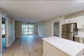 This 2-bedroom, 2-bathroom residence offers a thoughtfully designed single-floor layout that maximizes both comfort and functionality. Light hardwood flooring flows throughout the main living areas, lending a bright and cohesive aesthetic. The open-concept kitchen is a standout feature, equipped with white shaker cabinetry, a classic white subway tile backsplash, quartz countertops, a marble-look island, and a full suite of stainless steel appliances including a refrigerator, dishwasher, electric range, and built-in microwave. The kitchen transitions seamlessly into the living room, which benefits from large sliding glass doors that fill the space with natural light and offer views of surrounding greenery. The primary bedroom is a generously sized retreat with a dedicated window framing outdoor tree views. The second bedroom also features a bright window with natural light. Both bathrooms are finished with light tile flooring and white cabinetry, with one featuring a tub-shower combination and extended vanity. Two closets provide ample storage. Warm neutral-toned walls and clean white trim carry throughout every room, creating a calm, move-in-ready environment.