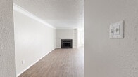 This single-story, 2-bedroom, 2-bathroom home delivers a functional and comfortable layout across a well-utilized footprint. The living room serves as the heart of the home, featuring warm wood-look flooring, crown molding, a textured ceiling, and a classic fireplace flanked by built-in shelving. A ceiling fan and multiple windows allow for abundant natural light, creating a bright, open atmosphere.

The kitchen is outfitted with white cabinetry, light stone-patterned countertops, a double stainless steel sink with a brushed nickel pull-down faucet, and stainless steel appliances, offering a clean and practical workspace.

Both bedrooms continue the wood-look flooring and neutral color palette. The primary bedroom, a generously sized room, includes a large window and direct access to a spacious walk-in closet with dual rows of built-in shelving and hanging rods. A second walk-in closet provides additional storage.

The bathrooms feature light countertops with undermount sinks and a tub-shower combination, maintaining the home's consistent, clean aesthetic. A dedicated hallway and entrance area complete the efficient floor plan, ensuring smooth flow between all rooms. The overall ambiance is neutral, move-in ready, and well-suited for everyday living.