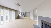 Located at 7000 S Paradise Rd in Las Vegas, Nevada, this single-floor residence offers a clean, modern aesthetic defined by a neutral gray color palette, light wood-look flooring, and white trim throughout. The open-concept living and dining area flows seamlessly into the kitchen, anchored by a tiled fireplace that serves as a focal point in the main living space. Sliding glass doors with vertical blinds allow natural light to fill the room while providing outdoor access.

The kitchen is well-appointed with gray shaker-style cabinetry, granite-look countertops, a peninsula with bar seating potential, and a full suite of stainless steel appliances including a refrigerator, range, microwave, and dishwasher. Recessed lighting and a window above the sink add both function and brightness.

The bedrooms feature the same light flooring, ceiling fans, and ample natural light from well-placed windows. One bedroom includes a walk-in closet, adding practical storage. The bathroom is finished with a backlit vanity mirror, granite-look countertop, white cabinetry, matte black fixtures, and a tub-shower combination. The overall design is cohesive and modern, making this a well-maintained, move-in-ready space in the heart of Las Vegas.