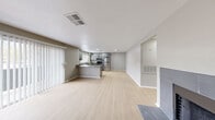 Located at 7000 S Paradise Rd in Las Vegas, Nevada, this single-floor residence offers a clean, modern aesthetic defined by a neutral gray color palette, light wood-look flooring, and white trim throughout. The open-concept living and dining area flows seamlessly into the kitchen, anchored by a tiled fireplace that serves as a focal point in the main living space. Sliding glass doors with vertical blinds allow natural light to fill the room while providing outdoor access.

The kitchen is well-appointed with gray shaker-style cabinetry, granite-look countertops, a peninsula with bar seating potential, and a full suite of stainless steel appliances including a refrigerator, range, microwave, and dishwasher. Recessed lighting and a window above the sink add both function and brightness.

The bedrooms feature the same light flooring, ceiling fans, and ample natural light from well-placed windows. One bedroom includes a walk-in closet, adding practical storage. The bathroom is finished with a backlit vanity mirror, granite-look countertop, white cabinetry, matte black fixtures, and a tub-shower combination. The overall design is cohesive and modern, making this a well-maintained, move-in-ready space in the heart of Las Vegas.