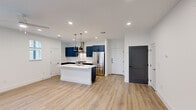 This well-designed two-story home in Leander, Texas offers a thoughtful layout across two floors. The main level features an open-concept kitchen and living area anchored by a striking kitchen with bold navy blue shaker-style cabinetry, a white subway tile backsplash, stainless steel appliances including a gas range with a wall-mounted hood, and a large center island with a white countertop and pendant lighting. Light hardwood-style flooring flows throughout, complementing the clean white walls and recessed lighting. Contrasting dark interior doors add a modern design accent throughout the home. The main floor also includes a garage with utility access. Upstairs, three bedrooms provide comfortable living space, including a generously sized primary suite complete with a walk-in closet featuring dual hanging rods and built-in shelving, and a private en-suite bathroom with gray vanity cabinetry, white countertops, and a glass-enclosed tile shower. The additional bedrooms are bright and airy, each benefiting from natural light through large windows. With three full bathrooms serving all occupants, this home balances practicality and modern style in a clean, move-in-ready package.