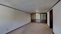 Located at 2350 Appleridge Dr in Columbus, Ohio, this single-story home offers a straightforward and functional layout. The main living area is a defining feature of the space, showcasing a striking wall of built-in dark wood shelving and cabinetry that spans floor to ceiling. These built-ins provide generous storage and display space, lending a classic, structured character to the room. A ceiling fan with a light fixture is centrally mounted, offering both air circulation and ambient lighting. The floors are covered in neutral-toned carpet, contributing to a warm and quiet underfoot feel throughout. Walls are painted in a clean, light tone, complemented by dark trim that echoes the rich wood tones of the built-in cabinetry. The ceiling features a textured popcorn finish, consistent with the architectural style of the era. The overall ambiance of the home is practical and solid, with built-in storage elements that add both utility and visual interest. The single-floor layout offers ease of navigation and accessibility throughout the property, making it a functional and straightforward living space in a residential Columbus neighborhood.