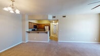 This single-floor residence offers a functional and comfortable layout designed for everyday living. The open-concept living and dining area is finished with plush wall-to-wall carpeting and neutral-toned walls, creating a warm and inviting atmosphere. A tiled entryway leads into the main living space, which features a ceiling fan and a vertical blind-covered window that allows natural light to filter through.

The kitchen is thoughtfully designed with rich medium-toned wood cabinetry, granite-style countertops, and tile flooring. It is fully equipped with stainless steel refrigerator, a gas range, and a built-in microwave. A peninsula with bar seating provides a seamless connection between the kitchen and the living area, making it ideal for casual dining or entertaining.

A hallway leads to the private quarters of the home. The bedrooms are carpeted and finished with the same warm neutral palette seen throughout the unit. One bedroom includes access to a walk-in closet with wire shelving, providing ample storage.

The bathrooms are well-appointed; one features a full tub/shower combo, tile flooring, and a wood vanity with granite-style countertops, while another includes a double-sink vanity with a large framed mirror and a generously lit vanity bar—ideal for a primary suite setting.