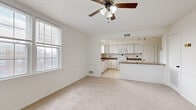 This well-appointed single-floor residence offers four bedrooms and one bathroom across a generous, thoughtfully laid-out floor plan. The open-concept kitchen and living room serve as the heart of the home, where plush carpeting flows through the living area and transitions to tile flooring in the kitchen. The kitchen is equipped with white cabinetry, granite-style countertops, a white appliance suite including a range and refrigerator, a breakfast bar peninsula, and track lighting overhead. A ceiling fan with a light fixture anchors the living room, which benefits from natural light through large windows fitted with blinds.

The spacious primary bedroom is notably generous in size, featuring soft carpet, bright windows, and a clean, neutral palette. The three additional bedrooms are well-proportioned, each with carpeted floors and windows that allow ample natural light. The hallways connect the rooms efficiently, with one entry area featuring a built-in coat hook rack and white tile flooring, providing a practical mudroom-style transition space. Throughout the home, crisp white walls and neutral tones create a clean, versatile backdrop. The overall ambiance is bright, airy, and move-in ready.