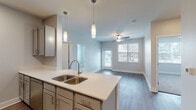 Located at 1375 Yost St in Aurora, Colorado, this single-floor residence showcases a contemporary design with a neutral color palette and thoughtful finishes throughout. The open-concept living and kitchen area serves as the heart of the space, where warm wood-look plank flooring extends seamlessly from the kitchen peninsula into the living area. A ceiling fan provides comfort overhead, while windows along the exterior wall invite natural light and views of the surrounding neighborhood.

The kitchen is well-appointed with gray shaker-style cabinetry, light quartz countertops, and a full suite of stainless steel appliances, including a range, microwave, and dishwasher. A central island with a double-basin sink and elegant pendant lighting above adds both functionality and style.

The bedroom features plush carpeting, multiple windows with blinds, a ceiling fan, and generous natural light. Storage is a standout feature, with spacious walk-in closets outfitted with wire shelving systems and carpeted floors. The bathroom is accessible via a hallway and continues the wood-look flooring found throughout the main living areas. The overall ambiance is clean, bright, and move-in ready.