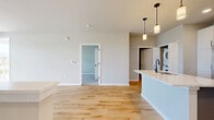 Located at 1211 Carrington Blvd in Mount Pleasant, WI, this modern 1-bedroom, 1-bathroom unit offers 770 square feet of well-appointed single-floor living. The open-concept kitchen and living room serve as the heart of the home, featuring light hardwood-style flooring that flows throughout. The kitchen is a standout, equipped with two-tone cabinetry — white upper cabinets paired with gray lower cabinets — complemented by white quartz countertops, a large center island with a matte black faucet, stainless steel appliances including a French door refrigerator and electric range, and a built-in microwave. Matte black hardware accents tie the design together cohesively. The adjacent living room is bright and airy, with large windows and a glass panel door offering outdoor views and ample natural light. The 140-square-foot bedroom features plush carpet flooring and oversized windows that frame pleasant exterior views. The bathroom is finished with warm wood-look tile flooring, dark cabinetry, a white vanity countertop, and matte black fixtures and towel bars. A dedicated closet provides added storage, and an in-unit stacked washer and dryer adds everyday convenience.