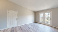 Located at 4250 Branch Bend Ln in Charlotte, NC, this single-floor, 2-bedroom, 2-bathroom residence offers a clean, functional layout designed for comfortable everyday living. The open living room features light wood-style laminate flooring and neutral warm-toned walls, with a textured ceiling overhead. A pair of French doors floods the space with natural light and opens directly to a private balcony with outdoor views. The galley-style kitchen is bright and efficiently organized, featuring white cabinetry with black hardware, a dual-basin sink, a white electric range, a refrigerator, and a peninsula counter that separates the kitchen from the living area. Both bedrooms are carpeted and finished with the same neutral palette, offering a calm and restful atmosphere, each with access to closet storage. The primary bedroom is a comfortable, well-proportioned room. The bathrooms are finished with wood-style flooring, white vanities with under-cabinet storage, and tiled shower-tub combinations with black accent hardware. Two hallways connect the rooms throughout the unit, and the layout is supported by multiple closet spaces for ample storage throughout.