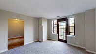 Located at 1380 E Hyde Park Blvd in Chicago's storied Hyde Park neighborhood, this single-floor unit offers a straightforward and functional layout across several well-defined rooms. The living area is a standout feature, showcasing large, dark-framed multi-pane windows that flood the space with natural light and frame views of the surrounding greenery. Plush carpeting runs throughout the main living and sleeping areas, adding warmth and comfort underfoot.

The bedrooms are comfortably sized, each carpeted and finished with neutral-toned walls. One bedroom benefits from a bright window with views of the outdoors, while another features a window with a deep sill, characteristic of the building's classic construction. The rooms offer clean lines and ample wall space, providing flexibility for furnishing.

The kitchen includes white cabinetry, a sink, and countertop space, offering a practical cooking environment. The bathroom is neatly appointed with a white vanity featuring cabinet storage, a mirror, chrome fixtures, and coordinating towel bars — presenting a tidy and cohesive finish.

A hallway with a closet connects the various rooms, contributing to an organized flow throughout the unit. The neutral color palette and consistent finishes give the space a calm, move-in ready character well-suited to the vibrant Hyde Park community.