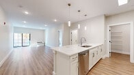 Located at 305 Patterson St in Hillsdale, NJ, this thoughtfully designed 2-bedroom, 2-bathroom residence offers a clean, modern aesthetic throughout its well-proportioned single-floor layout. Light wood-tone flooring and a neutral color palette create a bright, cohesive atmosphere across every room.

The open-concept kitchen and living area serves as the heart of the home. The kitchen features a large waterfall-edge island with an undermount sink, white shaker cabinetry, a subway tile backsplash, and a full suite of stainless steel appliances including a gas range, over-range microwave, refrigerator, and dishwasher. Elegant pendant lighting illuminates the island. The spacious living area extends naturally from the kitchen and opens to an outdoor space via large black-framed sliding glass doors that invite generous natural light and views of surrounding foliage.

The generously sized primary bedroom offers a tranquil retreat with a window framing colorful seasonal tree views. The second bedroom is equally well-appointed with warm wood flooring and ample wall space. Both bathrooms are finished in crisp white, with one featuring a soaking tub and subway-tiled shower surround, a white vanity, and large-format tile flooring. A dedicated laundry area houses a stacked washer and dryer unit alongside wire shelving for additional storage.
