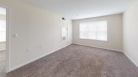 Unit 119 at 3420 Rickey Ave in Temple Hills, Maryland offers a well-designed single-floor layout that balances comfort and functionality. The living area is generously sized, featuring plush wall-to-wall carpeting, neutral beige walls, and a large window that allows an abundance of natural light to fill the space. A closet and utility access panel are conveniently integrated into the living area wall. The kitchen is positioned adjacent to the living space and is accessible via a pass-through counter, creating an open and connected feel. It is outfitted with white cabinetry, gray countertops, a double sink, a black refrigerator, a black range with overhead ventilation, and a dishwasher, all set atop durable tile flooring. The bedroom is a bright and comfortable retreat, featuring carpet flooring and two windows on separate walls, providing excellent natural light and cross-ventilation. The full bathroom is finished with large-format tile flooring, a wood-toned vanity with a sink and mirror, overhead vanity lighting, and a window for natural light. The unit presents a clean, move-in ready environment with a practical and cohesive design throughout.