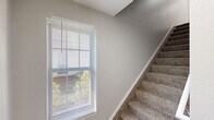 Located at 3675 Audrey Rae Lane in Howell, Michigan, this two-bedroom, two-bathroom home spans two floors and offers a thoughtfully designed layout with modern finishes throughout. A ground-level entrance leads upstairs, where the majority of the living space unfolds. The main living area is a standout, featuring striking vaulted ceilings and a ceiling fan, soft carpeting, and a window that fills the room with natural light, creating an open and airy atmosphere. The kitchen is well-equipped with crisp white shaker-style cabinetry, marble-style countertops, stainless steel appliances including a range and over-the-range microwave, and wood-look flooring. Both bathrooms are finished with white vanities, marble-style countertops, and matte black hardware accents, with wood-look tile flooring adding warmth. The primary bedroom is generously sized with vaulted ceilings, a ceiling fan, carpeted floors, a window with outdoor views, and a walk-in closet with built-in shelving. The second bedroom is carpeted and bright, with a window and a double-door closet conveniently adjacent to the kitchen. A dedicated laundry area with a washer and utility shelving rounds out the home's practical amenities.