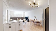 Located at 1387 Central Ave in Memphis, TN, this efficiently designed one-bedroom, one-bathroom unit makes excellent use of its compact footprint. Light wood flooring runs throughout, creating a warm, cohesive feel across all rooms.

The open-plan living, dining, and kitchen area serves as the heart of the unit. The living space features large windows with horizontal blinds that allow ample natural light, dark wainscoting panels along the lower walls, and a textured ceiling. A bold Sputnik-style chandelier with brass accents adds a modern, stylish touch. The kitchen is well-appointed with white shaker cabinets, marble-look countertops, a herringbone tile backsplash, stainless steel appliances including a range and over-the-range microwave, and a dedicated in-unit washer. The dining area comfortably accommodates a four-person table adjacent to the kitchen.

The bedroom offers a serene retreat, featuring a ceiling fan with light, large windows for natural brightness, and access to two closets for generous storage. The bathroom showcases a clean, contemporary aesthetic with a wood-slat vanity, matte black fixtures, a hexagonal mirror, and a full tub-shower combination framed by marble-look wall panels.