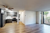 Located at 250 S Whiting St in Alexandria, Virginia, this one-bedroom, two-bathroom residence offers a well-organized single-floor layout designed for comfortable everyday living. Hardwood-style flooring runs throughout the main areas, lending a clean, cohesive aesthetic to the space.

The living room is a bright, open area anchored by a floor-to-ceiling sliding glass door that opens onto a private balcony with outdoor seating. A striking exposed brick accent wall adds architectural character and warmth to the room. The adjacent dining area flows naturally from the living space, creating a seamless open-plan layout.

The kitchen is well-appointed with dark gray cabinetry, stainless steel appliances including a refrigerator, electric range, and microwave, and a clean white countertop with a sink. A dedicated laundry area with a stacked washer and dryer unit is conveniently tucked nearby, along with additional closet storage.

The spacious primary bedroom receives generous natural light through large windows fitted with vertical blinds, offering a calm, airy retreat. Three closets throughout the unit provide ample storage.

Both bathrooms are finished with neutral tile flooring and white fixtures, including a full tub-shower combination. Hallways connecting the rooms are accented with the same exposed brick detailing seen in the living area, reinforcing the space's distinctive character.