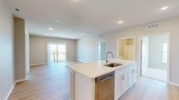 This well-appointed 3-bedroom, 2-bathroom residence in Norwalk, Iowa offers a thoughtfully designed single-floor layout that balances comfort and modern style. The open-concept kitchen and living area serves as the heart of the home, featuring crisp white shaker cabinetry, a large center island with an integrated sink, stainless steel appliances, light wood-look flooring, and recessed lighting throughout. Sliding glass doors connect the living area to a private balcony, offering pleasant views of the surrounding neighborhood and greenery. The bedrooms are carpeted for warmth and comfort, with ceiling fans and generous windows that invite abundant natural light and outdoor views. The spacious primary bedroom includes a dedicated walk-in closet fitted with wire shelving systems for organized storage. Both bathrooms are finished with white vanity cabinetry, clean countertops, and light wood-look flooring. The full bathroom features a tub-shower combination with a chrome curtain rod. Additional closets throughout the unit provide ample storage. The overall aesthetic is clean and contemporary, with neutral warm-gray tones, white trim, and a bright, airy ambiance carried consistently through every room.