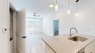 Located at 760 NW Shoal Creek Parkway in Kansas City, MO, this well-appointed 2-bedroom, 2-bathroom single-floor residence offers a clean, modern aesthetic throughout. The open-concept kitchen and living area serves as the heart of the home, featuring light wood-style flooring, crisp white walls, and a ceiling fan that enhances the airy feel. The kitchen is equipped with white shaker cabinetry, sleek quartz countertops, stainless steel appliances including a range and built-in microwave, a subway tile backsplash, and a kitchen island with an undermount sink and stylish pendant lighting. The living room receives ample natural light through large windows dressed with horizontal blinds, and opens to a private balcony. Both bedrooms are generously sized, finished with plush carpet and ceiling fans. The spacious primary bedroom includes a walk-in closet outfitted with wire shelving systems. The bathrooms are finished with white cabinetry featuring matte black hardware, quartz countertops, and tiled shower surrounds. Two dedicated closets provide excellent storage throughout. A connecting hallway ties all spaces together seamlessly, completing this thoughtfully designed residence.