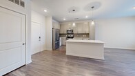 Located at 2700 E College Ave in Decatur, GA, this well-appointed one-bedroom, one-bathroom apartment offers a thoughtfully designed open-concept layout across a single floor. The combined living, dining, and kitchen area serves as the heart of the home, featuring wood-style plank flooring, crisp white walls, and abundant natural light from large windows and a glass patio door. The modern kitchen is equipped with stainless steel appliances—including a refrigerator, range, microwave, and dishwasher—complemented by light wood cabinetry, a mosaic tile backsplash, and a spacious central island with quartz countertops and stylish gold-accented pendant lighting. The living and dining areas flow seamlessly toward a private patio, offering outdoor access and views. The carpeted bedroom is generously sized, filled with natural light, and includes direct access to a walk-in closet outfitted with wire shelving. A second closet provides additional storage. The bathroom features large-format tile flooring, a wood-toned vanity with quartz countertop, and a full tub-shower combination. An in-unit laundry area adds everyday convenience, completing this modern and functional residence.