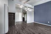 This single-story unit at 1730 Rogers Pl in Burbank, CA showcases a mid-century modern aesthetic defined by distinctive exposed beam ceilings with white-painted wood planking throughout the main living areas. The living room is a standout space, featuring soaring vaulted ceilings with natural wood beam detailing, dark hardwood-style flooring, and neutral gray walls that create a contemporary yet warm atmosphere. A large window with vertical blinds allows natural light to fill the room, while a ceiling fan adds functionality. A built-in shelving unit with lower cabinet storage provides practical storage solutions.

The kitchen is well-appointed with rich dark cabinetry, granite-style countertops, a gas range with overhead ventilation hood, and a window that brings in additional natural light. The bedroom continues the beam ceiling aesthetic, featuring carpeted flooring, soft gray walls, and a window with outdoor views. A secondary room with a bold dark accent wall and the same wood-style flooring offers flexible use as a bedroom or living space. The bathroom is clean and functional, featuring wood-style flooring, a window for natural ventilation, and a streamlined vanity. Overall, the space presents a cohesive, modernized mid-century character throughout.