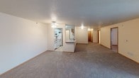 This single-floor unit features two bedrooms and two full bathrooms within a well-organized layout. The open living and dining area provides generous room for everyday use, finished with neutral-toned carpet and a textured ceiling throughout. A sliding glass door with vertical blinds introduces natural light and connects the living space to the outdoors. The kitchen is designed in a galley configuration, featuring white cabinetry with wood trim, a double-basin stainless steel sink, white appliances including a coil-top range and built-in microwave, and a skylight-style overhead fixture that brightens the space. A peninsula counter separates the kitchen from the main living area, offering convenient pass-through functionality.

The two bedrooms are carpeted and provide comfortable living spaces, with wood-trimmed doors and access to closets. One bedroom includes a window with a view to the exterior. The primary bathroom features a single-sink vanity with wood-accented cabinetry and a well-lit mirror, while the second bathroom includes a full tub-shower combination, a matching vanity, and tile-style flooring. Both bathrooms maintain a clean, neutral aesthetic consistent with the rest of the unit.