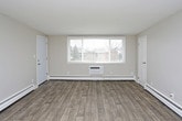 This single-floor residence offers a thoughtfully designed layout with a clean, updated aesthetic throughout. The kitchen is a standout feature, showcasing crisp white shaker cabinetry, gray stone countertops, a classic white subway tile backsplash, a stainless steel double-basin sink, and a stainless steel range. Light wood-look flooring ties the kitchen and living areas together, creating a cohesive and contemporary feel. The open living area is generously sized, featuring a ceiling fan and baseboard heating, with a natural flow into the kitchen. Multiple bedrooms are finished with neutral wall tones and plush wall-to-wall carpeting, each offering sliding or panel-style closets and windows that bring in natural light. The primary bathroom includes a full tub-shower combination with tiled surround and wood-look flooring, while a second bathroom features a pedestal sink, a vanity mirror with overhead lighting, and matching flooring. Baseboard heating is present throughout the unit, ensuring consistent comfort. The overall ambiance is bright, clean, and move-in ready, with a neutral color palette that provides a versatile backdrop for any décor style.
