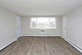 This single-floor residence offers a thoughtfully designed layout with a clean, updated aesthetic throughout. The kitchen is a standout feature, showcasing crisp white shaker cabinetry, gray stone countertops, a classic white subway tile backsplash, a stainless steel double-basin sink, and a stainless steel range. Light wood-look flooring ties the kitchen and living areas together, creating a cohesive and contemporary feel. The open living area is generously sized, featuring a ceiling fan and baseboard heating, with a natural flow into the kitchen. Multiple bedrooms are finished with neutral wall tones and plush wall-to-wall carpeting, each offering sliding or panel-style closets and windows that bring in natural light. The primary bathroom includes a full tub-shower combination with tiled surround and wood-look flooring, while a second bathroom features a pedestal sink, a vanity mirror with overhead lighting, and matching flooring. Baseboard heating is present throughout the unit, ensuring consistent comfort. The overall ambiance is bright, clean, and move-in ready, with a neutral color palette that provides a versatile backdrop for any décor style.