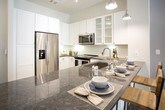 Located at 4558 Roswell Rd NE in Sandy Springs, Georgia, this single-floor residence offers a thoughtfully designed layout with modern finishes and a cohesive contemporary aesthetic throughout. The kitchen is a standout feature, showcasing crisp white cabinetry—including glass-front upper cabinets—dark granite countertops, a full suite of stainless steel appliances, and wood-look flooring. A large kitchen island with seating provides both prep space and a casual dining area, illuminated by a combination of pendant and track lighting. The living area is bright and inviting, with large windows that allow generous natural light and offer views of the surrounding exterior. A ceiling fan and track lighting provide flexible illumination, while the open layout creates a comfortable and functional gathering space. The bedroom is a serene retreat, featuring soft neutral wall tones, large windows with sheer curtains that bring in natural light, and ample room for a king-sized bed. The bathroom is finished with light tile flooring, a vanity with granite countertops, and a soaking tub with shower combination. A walk-in closet with built-in shelving and hanging rods is directly accessible from the bathroom, offering well-organized storage. This residence combines practical functionality with refined design details throughout.